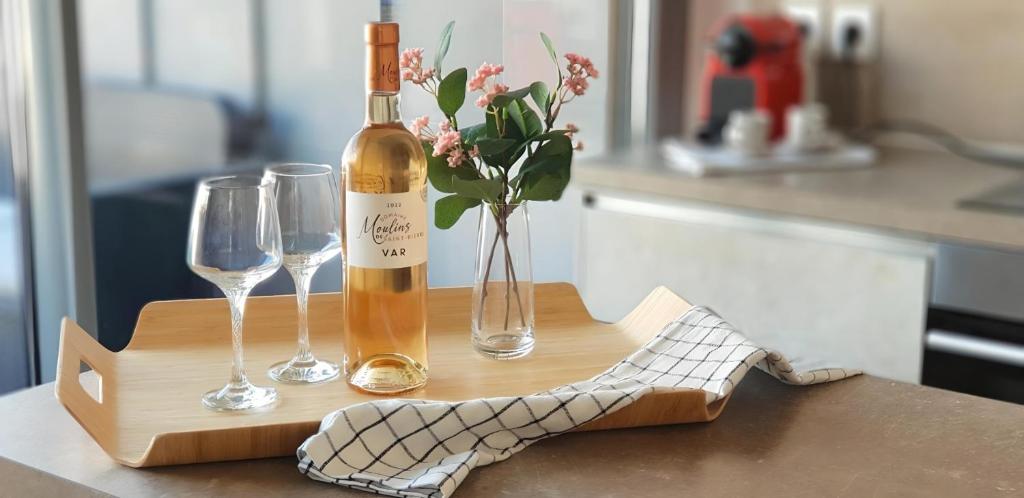 une bouteille de vin et deux verres sur une table dans l'établissement Modern Top-Floor Apartment with Terrace, Pool & Free Private Parking, à Roquebrune-Cap-Martin