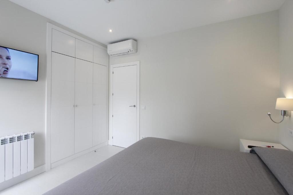 a white bedroom with a bed and a flat screen tv at Rincón de Gran Vía in Madrid