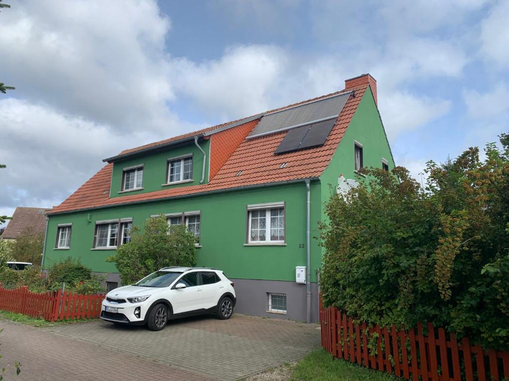 un coche blanco estacionado frente a una casa verde en Ferienwohnung Wieker Bodden, en Dranske