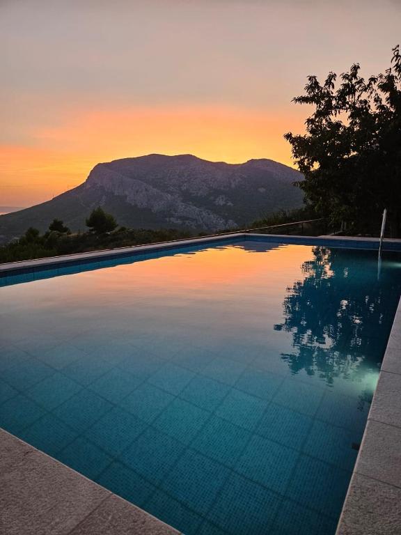 a swimming pool with a sunset in the background at Beverly Klis House in Klis