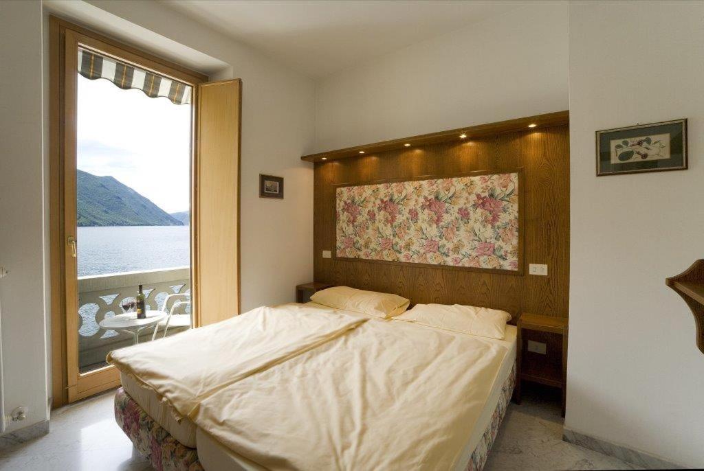 ein Schlafzimmer mit einem großen Bett und einem großen Fenster in der Unterkunft Lake Lugano Apartment - 14538 in Valsolda