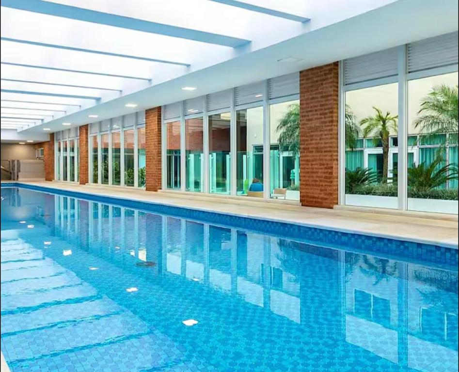 a large swimming pool in a building with windows at Studio Lifespace moderno no Batel in Curitiba