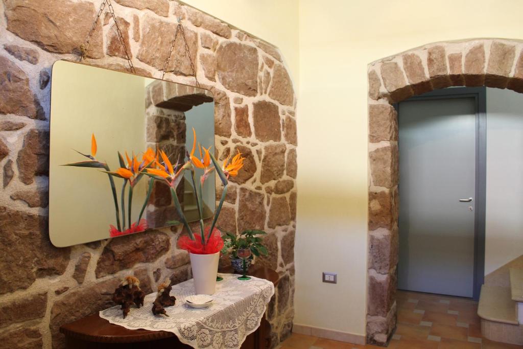 un couloir en pierre avec une table et un miroir dans l'établissement B&B Is Janas E5391, à Fordongianus