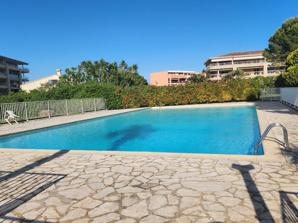 une grande piscine bleue en face de certains bâtiments dans l'établissement Studio lumineux à Antibes avec piscine, tennis et balcon - FR-1-789-10, à Antibes