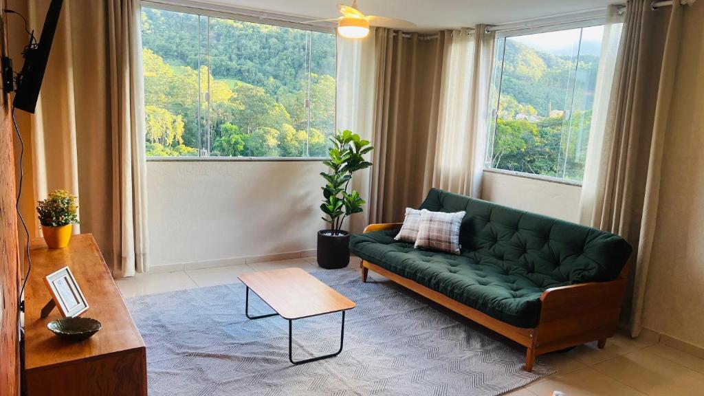 a living room with a green couch in front of a window at Apartamento novinho e aconchegante em Santa Teresa-ES, próximo da rua de lazer e parque de exposições in Santa Teresa