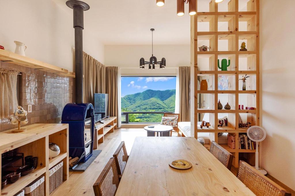 una cucina con tavolo in legno e una grande finestra di Gapyeong V Courtyard Pension a Gapyeong