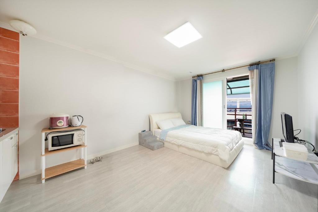 une chambre avec un lit et un micro-ondes dans l'établissement Yeosu Dream Green Pet-friendly Pension, à Yeosu