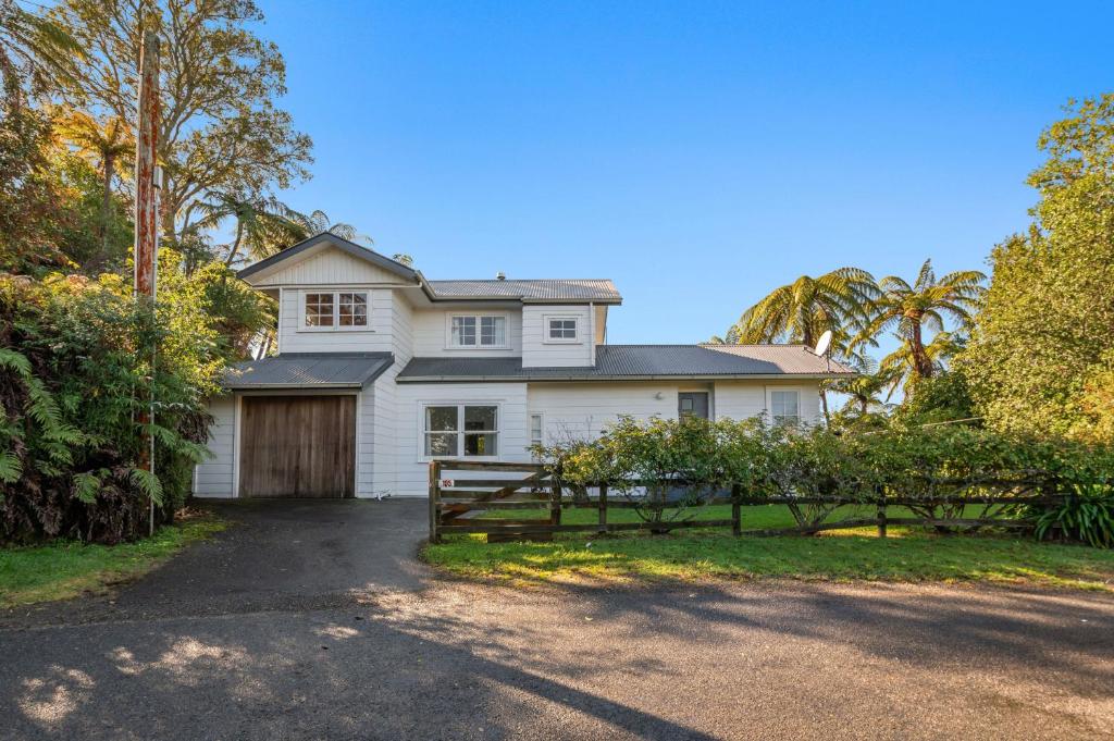 une maison blanche avec un portail et une allée. dans l'établissement Okere Retreat - Lake Rotoiti Getaway, à Okere Falls