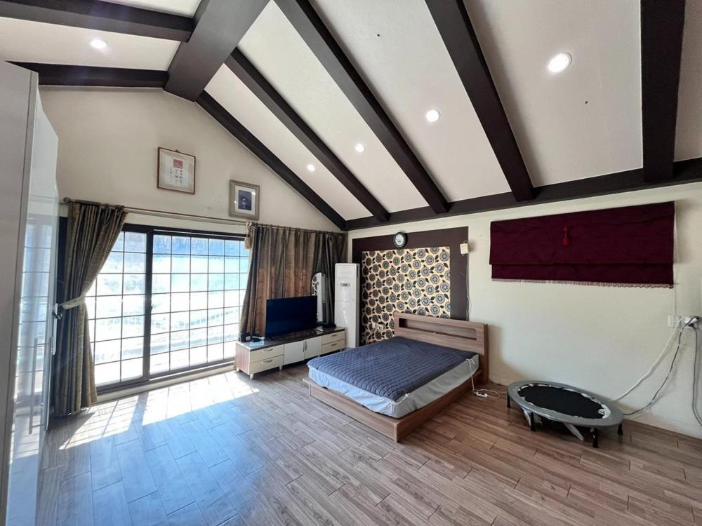 Un dormitorio con una cama y una ventana grande. en Gangneung Happy Pension, en Gangneung