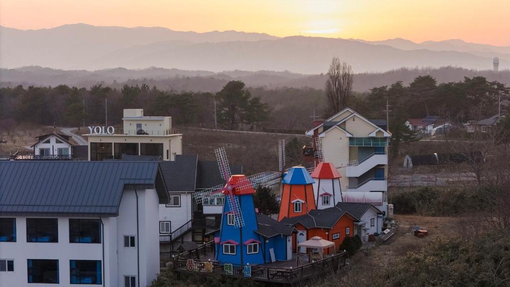 a group of houses with the sunset in the background at Gangneung Windmill Pension Pet friendly in Gangneung