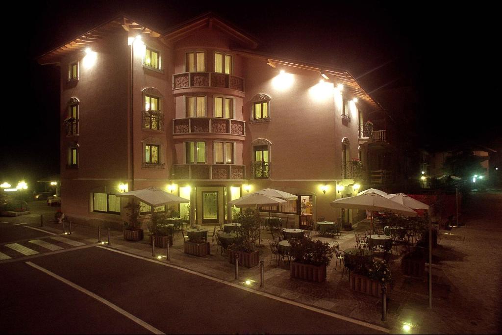 a building with tables and umbrellas in front of it at night at Hotel Mazzoleni in Roncola