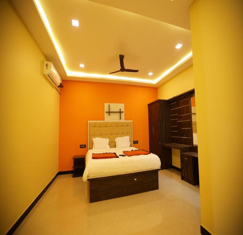 a bedroom with orange walls and a bed in it at The Canalway Inn in Pollāchi