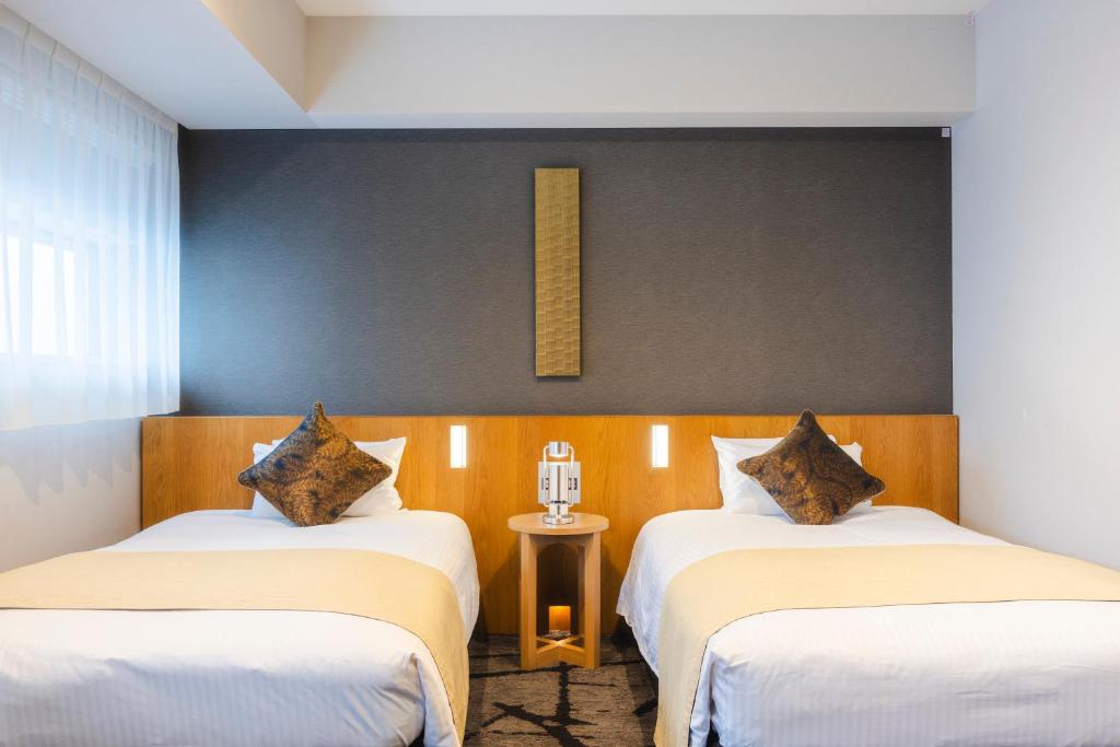 a room with two beds and a table at Hotel Gracery Shinjuku in Tokyo