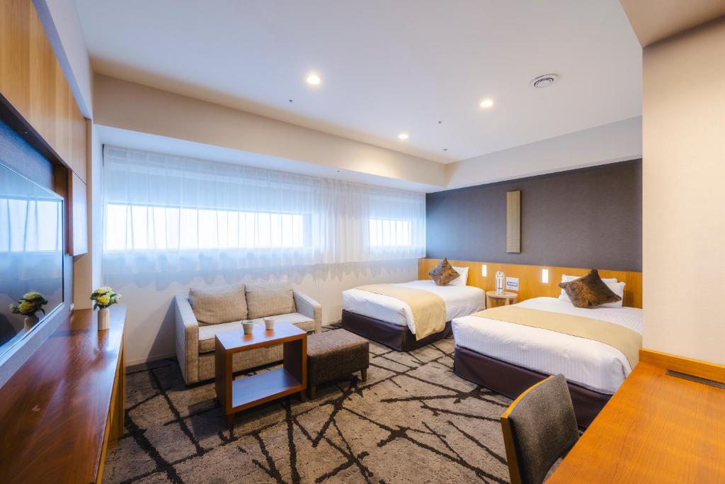 a hotel room with two beds and a couch at Hotel Gracery Shinjuku in Tokyo