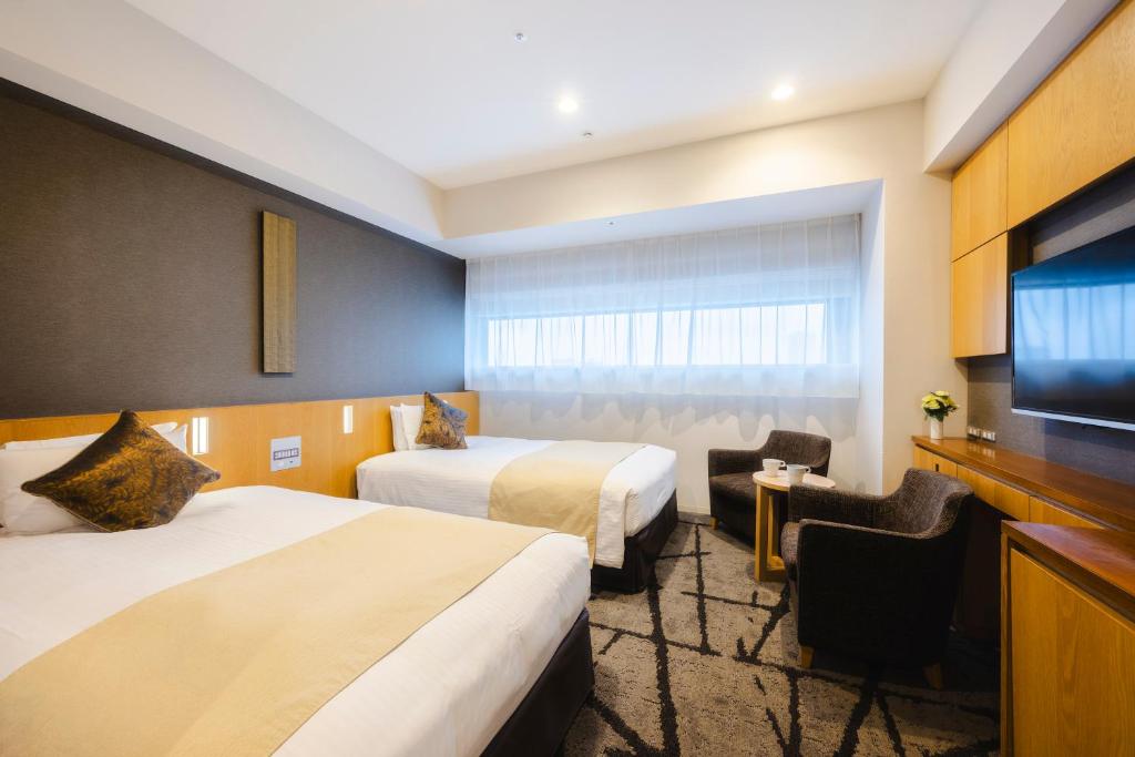 a hotel room with two beds and a flat screen tv at Hotel Gracery Shinjuku in Tokyo