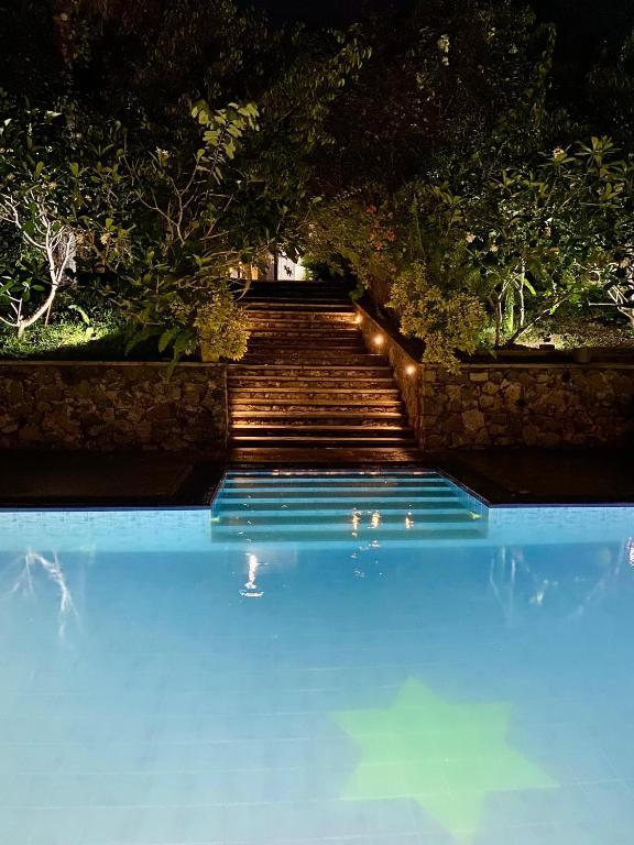 a swimming pool with stairs and blue water at The Nature Palace Villa in Ahungalla