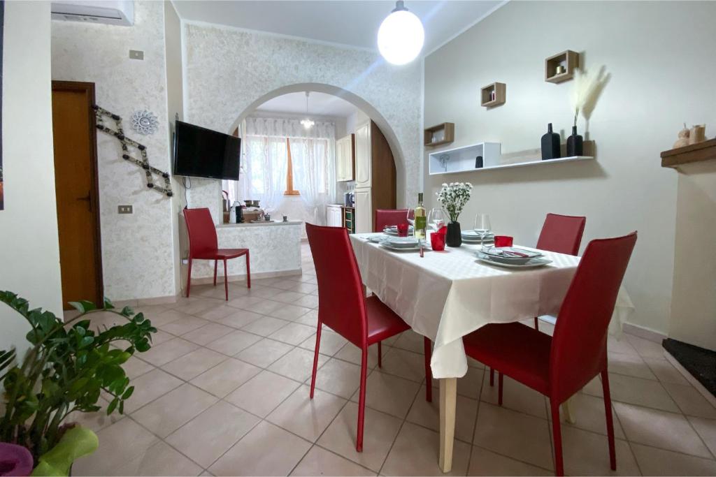 a dining room with a white table and red chairs at Civico 21 in Càbras