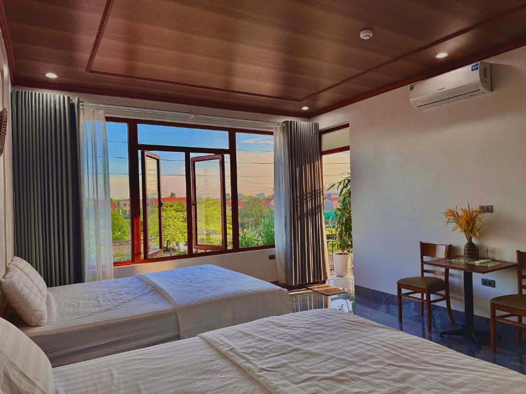 a bedroom with two beds and a large window at HANA Tam Coc Homestay in Văn Lâm