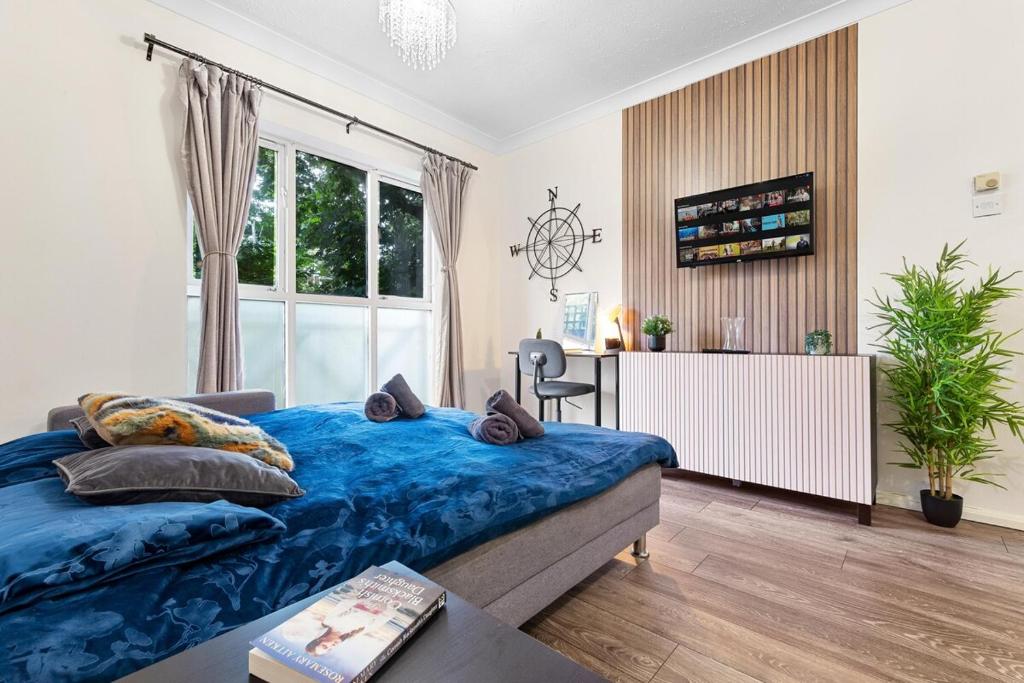 a bedroom with a blue bed and a desk and a window at Bright modern Flat near tower bridge in London