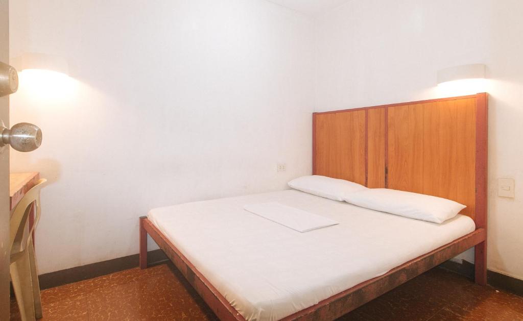 a small bedroom with a bed with a wooden headboard at Stay Malate Hostel by RedDoorz in Manila
