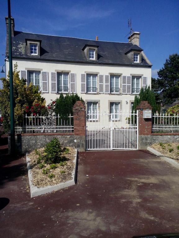 une grande maison blanche avec une clôture blanche dans l'établissement l'auberge du parachutiste, à Sainte-Mère-Église