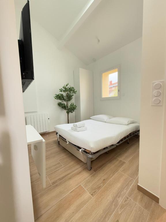 une chambre blanche avec un lit et une télévision dans l'établissement Cocoon by the Eiffel Tower and Roland Garros, à Paris