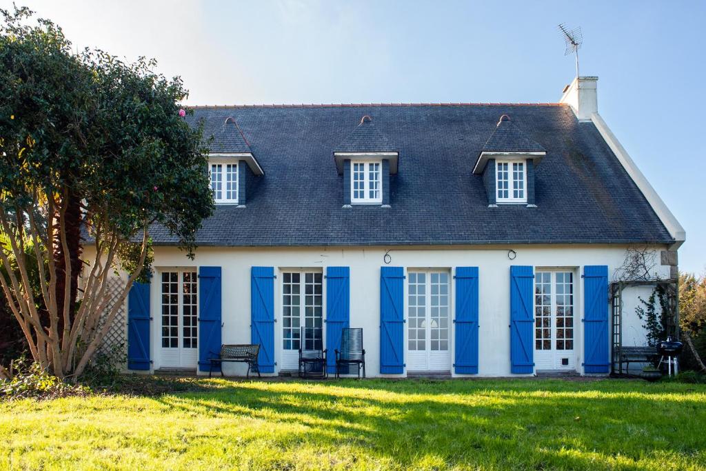 una casa azul y blanca con un patio en Maison Familiale vue mer et plage à pieds, en Ploubazlanec