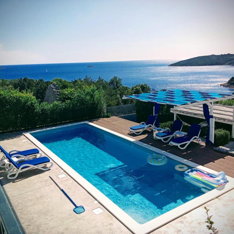 a swimming pool with a table and chairs and the ocean at LUXURY VILLA ŠENTADA in Vinišće