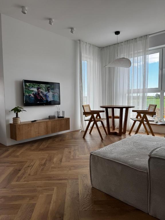a white living room with a table and a tv at Japandi Apartment Pogórze in Pogórze