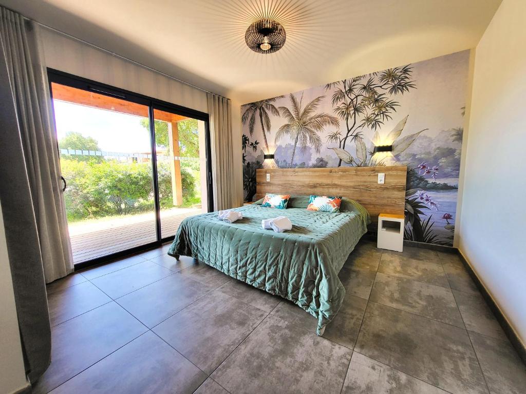 une chambre avec un lit et une grande fenêtre dans l'établissement Villas Lantana, à Porto-Vecchio