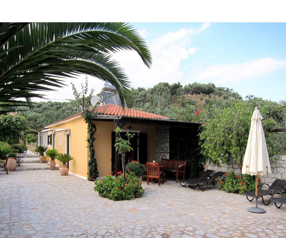 un patio con una mesa y una sombrilla y un edificio en Estia Holiday, en Gythio