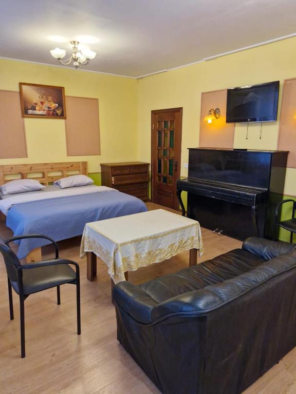 a bedroom with two beds and a couch and a piano at Apartament Erfolg 12 in Daugavpils