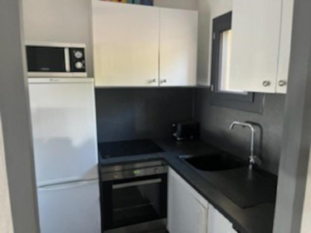 une petite cuisine avec des armoires blanches et un micro-ondes dans l'établissement ST Maxime, à Sainte-Maxime