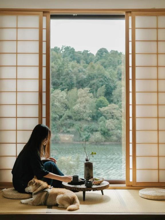 a woman sitting in front of a window with a dog at Come to Xipuman B&B in Baishi
