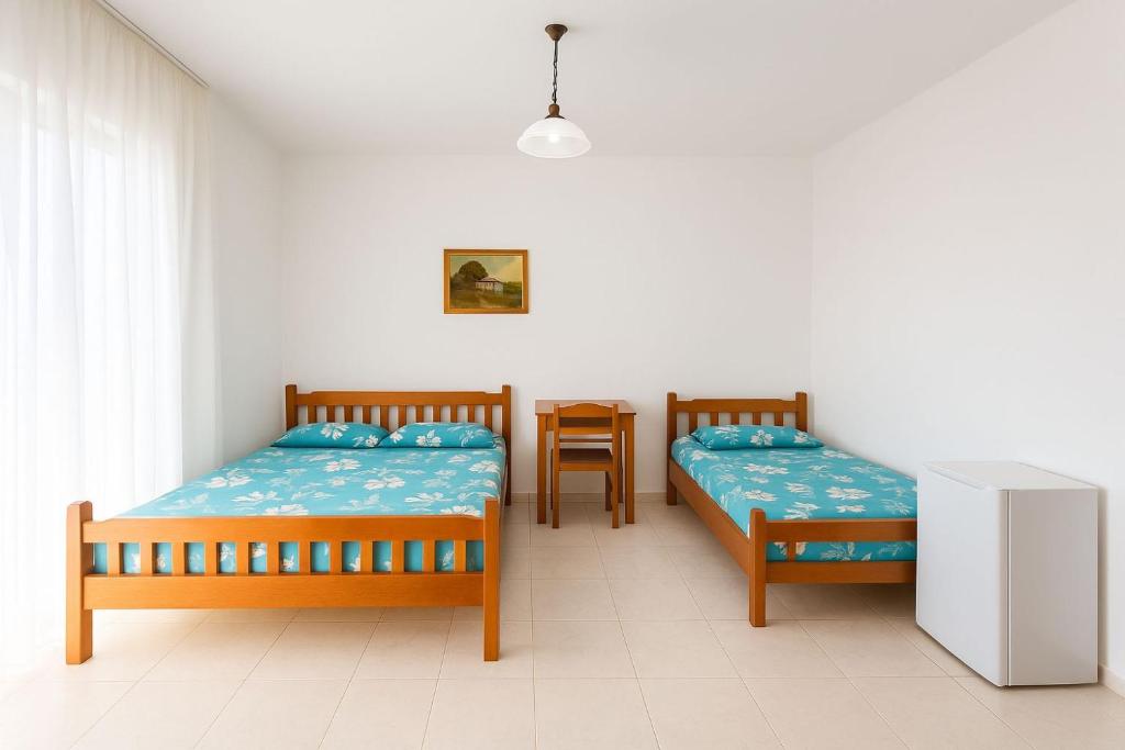 2 camas en una habitación con mesa y silla en Aura Rooms, en Durrës