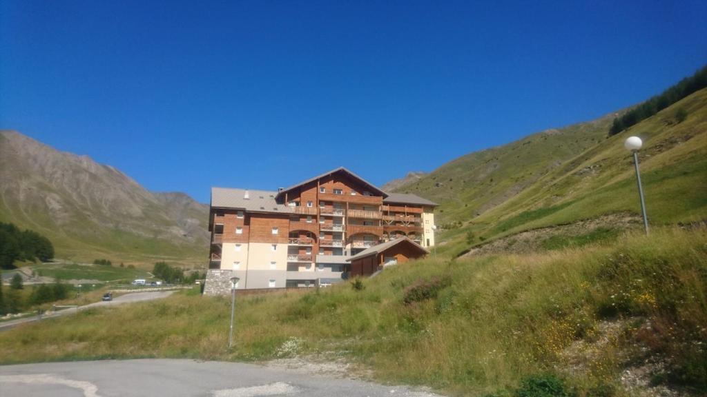 un bâtiment situé sur le côté d'une colline à côté d'une route dans l'établissement Appartement au pied de la montagne, à Allos