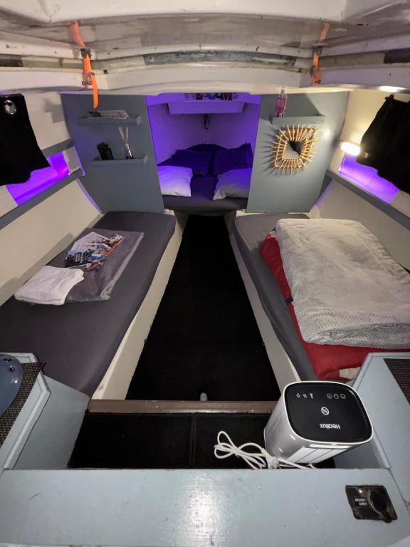 une chambre avec deux lits dans une camionnette avec des lumières violettes dans l'établissement Voilier Port Deauville avec parking privé gratuit, à Deauville