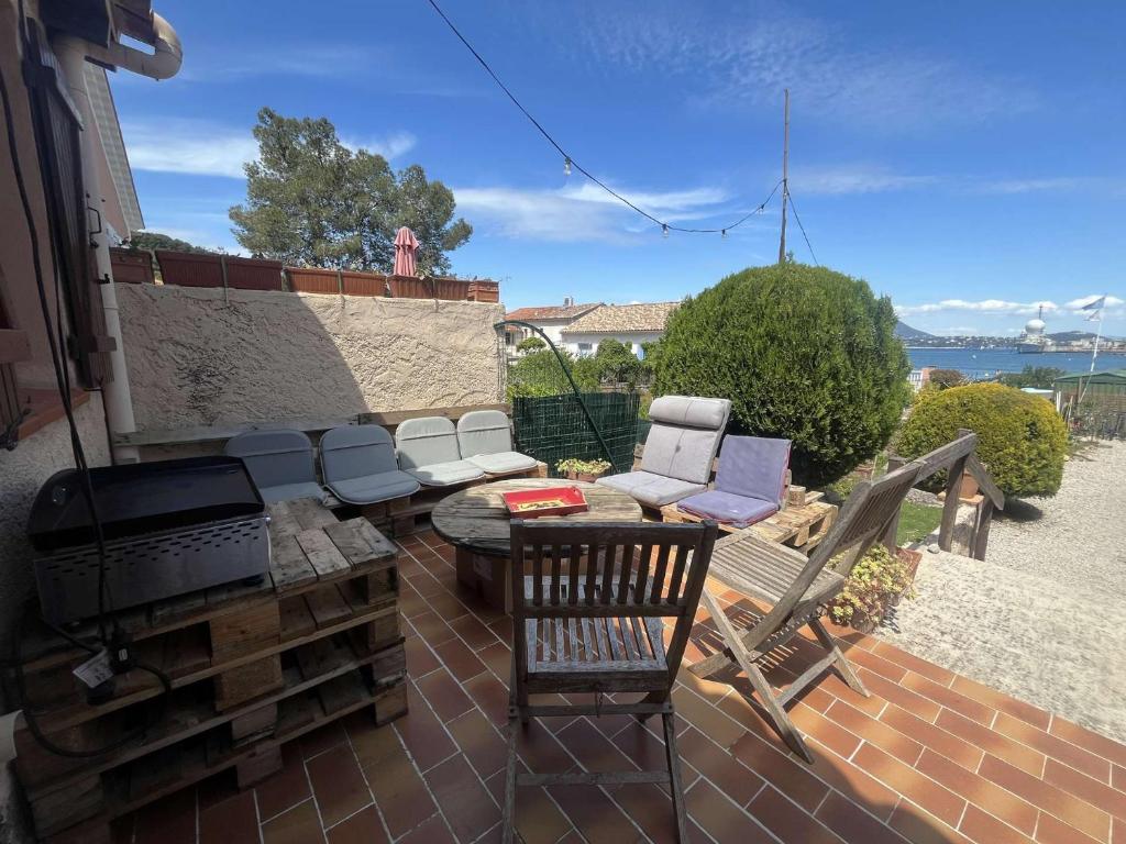 d'une terrasse avec un barbecue, des chaises et une table. dans l'établissement Maison de pêcheurs, Saint-Mandrier-sur-Mer, climatisation, vue mer, à Saint-Mandrier-sur-Mer