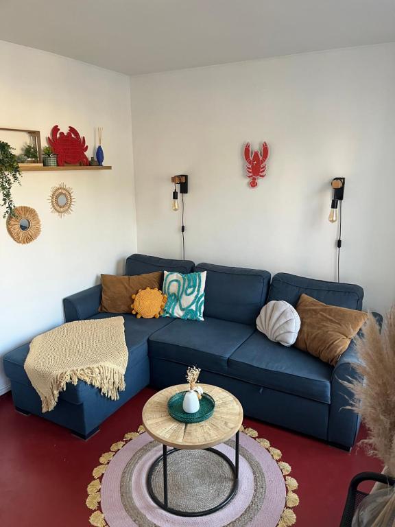 Una sala de estar con un sofá azul y una mesa. en La Perle des Falaises, en Le Tréport