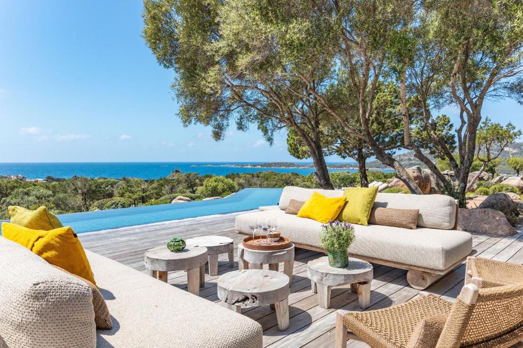 d'une terrasse avec des canapés et des tables donnant sur l'océan. dans l'établissement Casa Rocca Di Pianotolli, à Pianottoli-Caldarello
