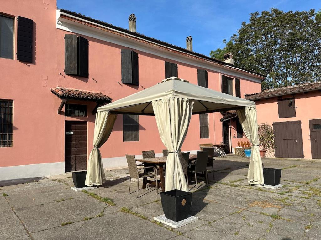 a white tent with chairs and a table in front of a building at Cascina Robusta three-room apartment Box Private parking in Sospiro