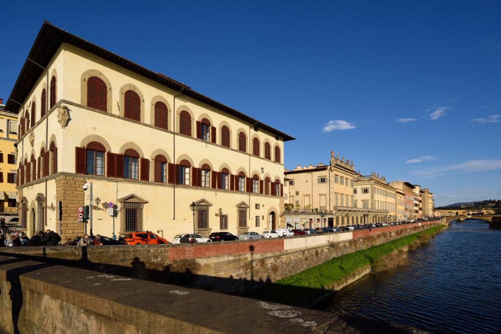 budynek nad rzeką, przy którym zaparkowane są samochody w obiekcie Leone Blu Suites | UNA Esperienze we Florencji