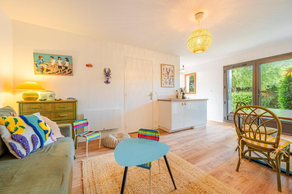 un salon avec un canapé, une table et des chaises dans l'établissement La Coquille / F3 de charme avec jardin privatif, à Cabourg