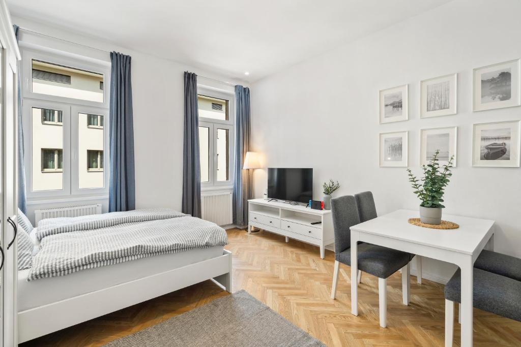 Hotel Bright and Quiet Apartments, Just 10 Minutes to U4, U6 and Schönbrunn Palace, a white bedroom with a desk and a bed and a table at Bright and Quiet Apartments, Just 10 Minutes to U4, U6 and Schönbrunn Palace in Vienna