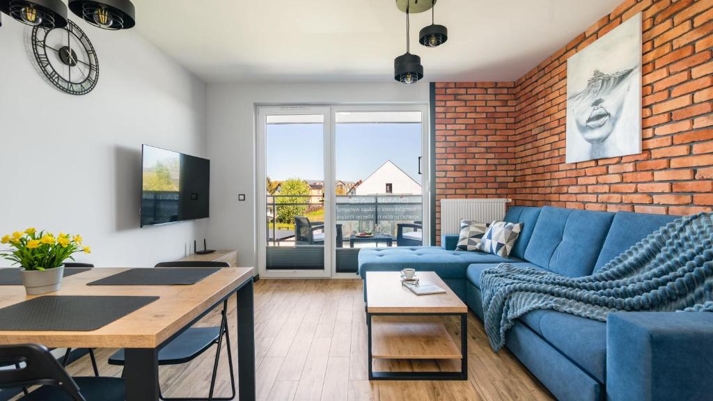 a living room with a blue couch and a brick wall at SOLE MARE Apartamenty Piamola z basenem in Kąty Rybackie