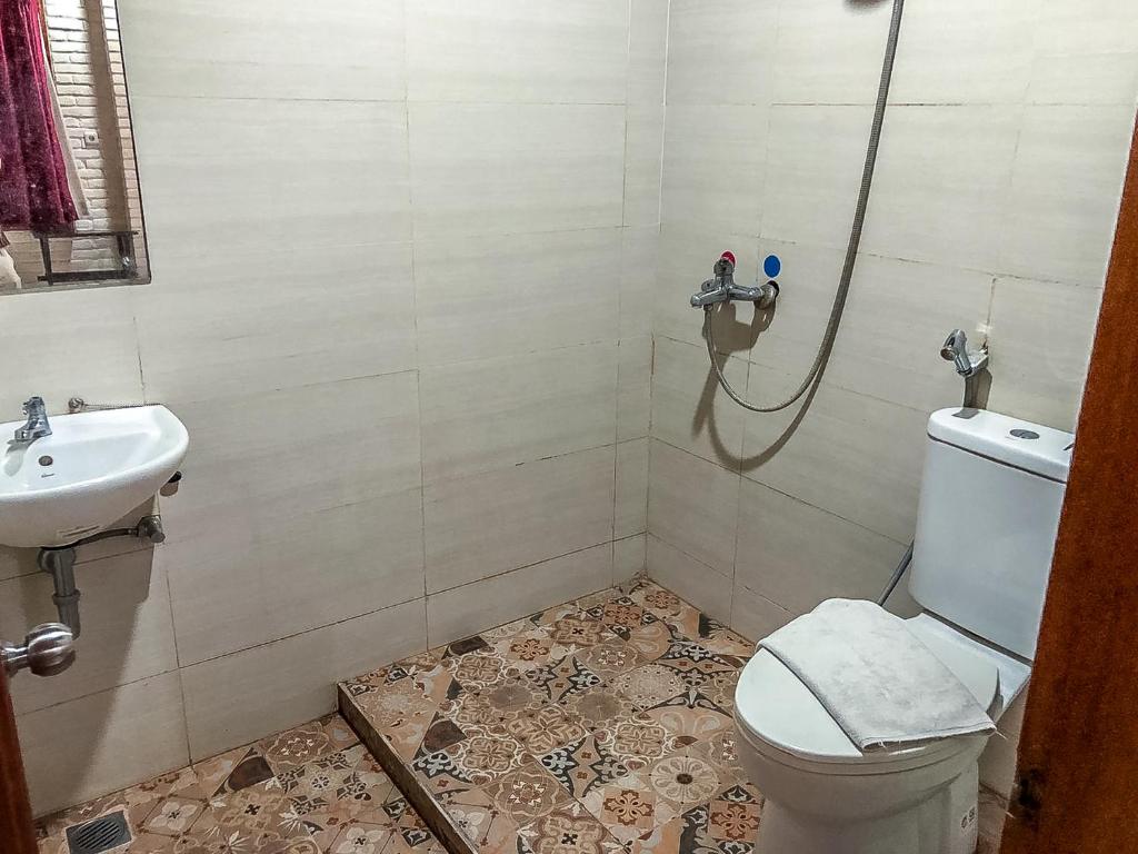 a bathroom with a shower and a toilet and a sink at Arys Garden Hotel Yogyakarta in Yogyakarta