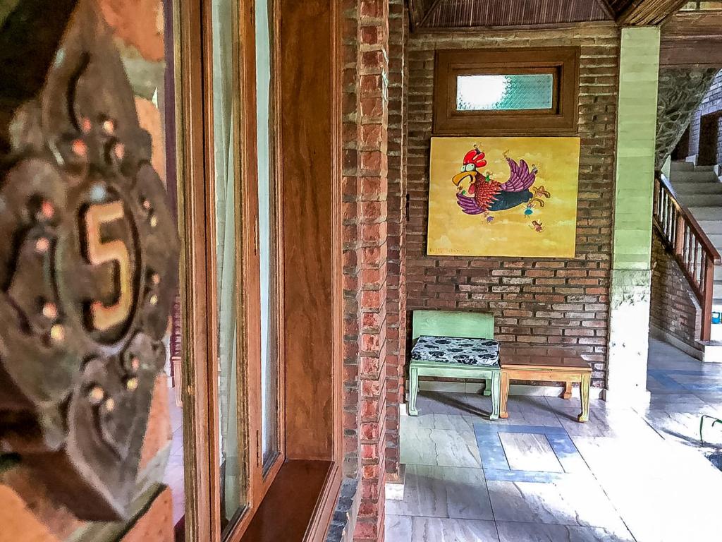 a room with a bench and a picture of a rooster at Arys Garden Hotel Yogyakarta in Yogyakarta