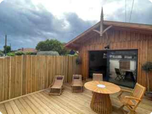 un patio avec une table et des chaises et une clôture dans l'établissement Cabane esprit Bassin à 100 mètres de la plage, à Arès