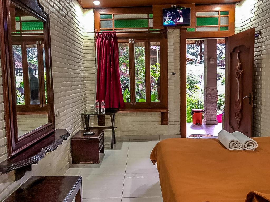 a bedroom with a bed and windows in a room at Arys Garden Hotel Yogyakarta in Yogyakarta