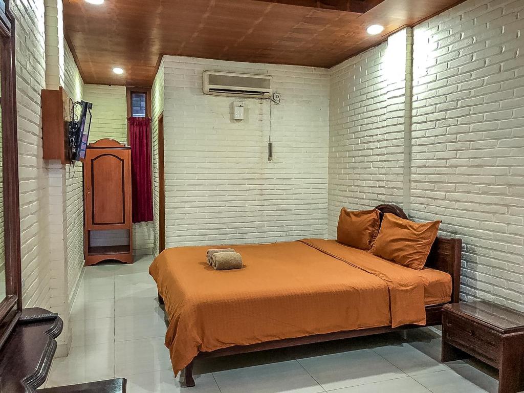 a bedroom with a bed with an orange blanket at Arys Garden Hotel Yogyakarta in Yogyakarta